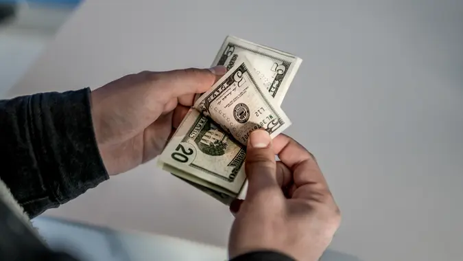 Unrecognizable young man counting US Dollar bills.