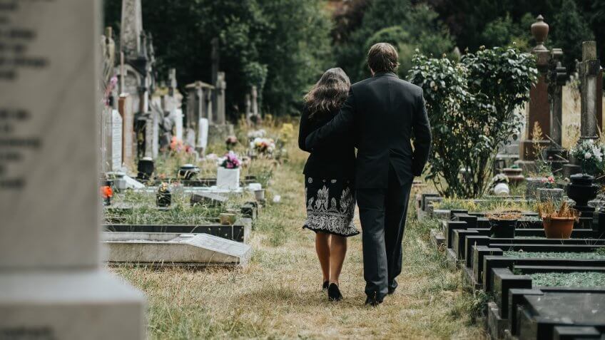 Sad couple walking through a cemetery.