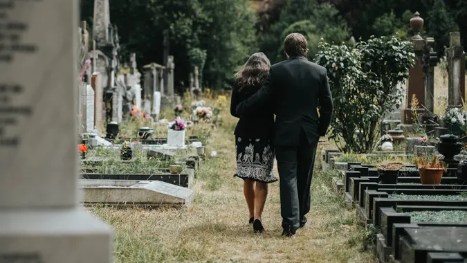 Sad couple walking through a cemetery.