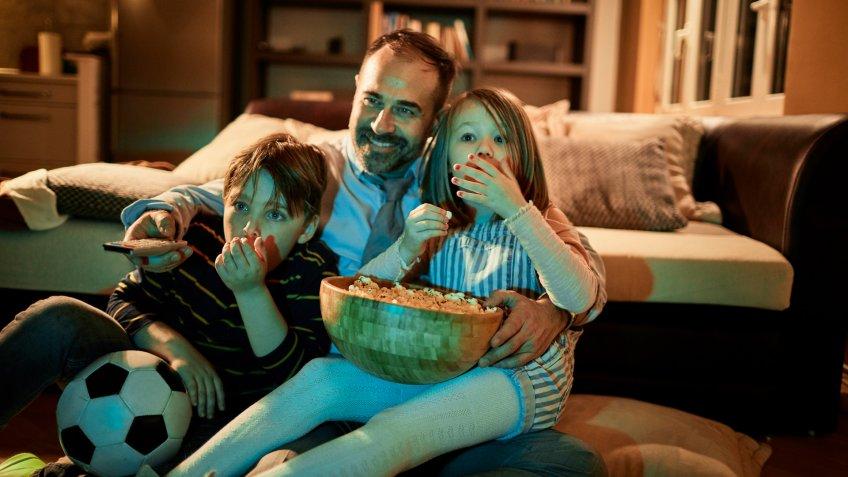 Close up of a father watching television with his kids.