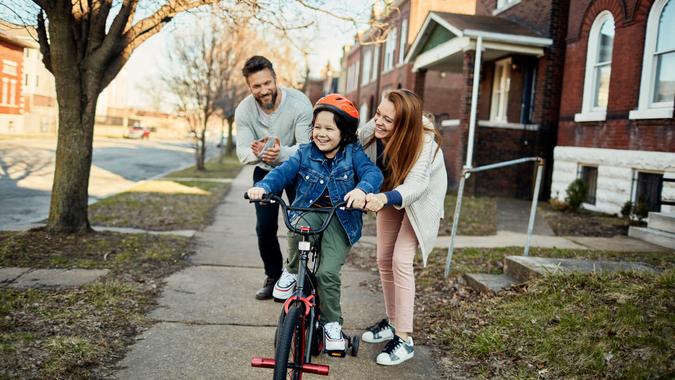 Close up of a father and mother helping their son with learning how to ride a bike.