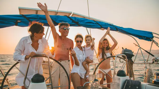 Group of different aged people having a party, dancing and drinking while sailing on sailboat.