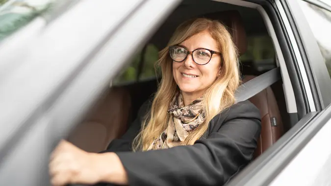 Portrait of a female driver smiling inside a car.