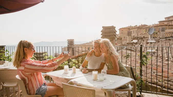 Three female friends sitting down at a table in a rooftop restaurant.