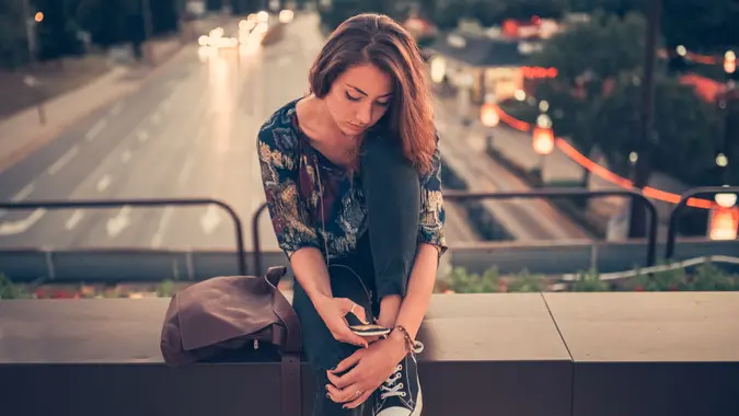 Young girl in the city surfing the net on cell phone.