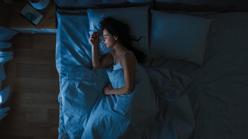 Top View of Beautiful Young Woman Sleeping Cozily on a Bed in His Bedroom at Night.