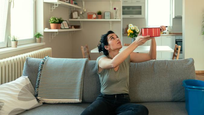 Shocked Woman Looks at the Ceiling While Collecting Water Which Leaks in the Living Room at Home.