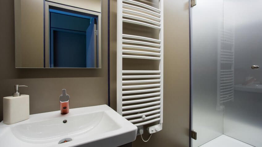 Fragment of the bathroom interior with sink and towel rail on the wall.