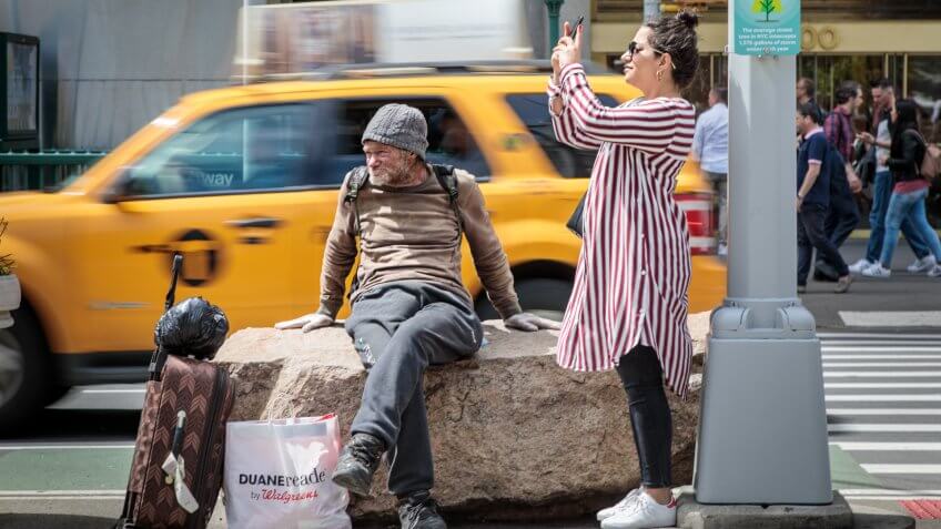 Flatiron building, Manhattan, New York, USA – May 11, 2018: A homeless man looking at the street life in front of the Flat Iron Building.