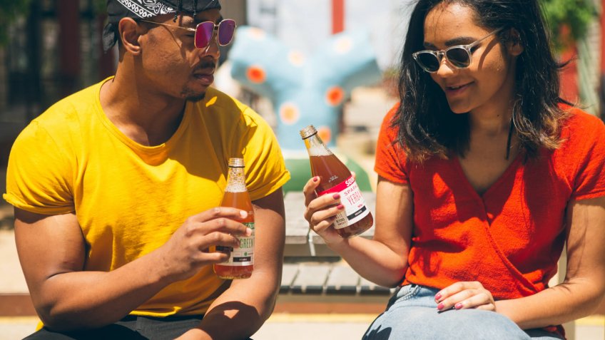 man and woman holding bottles of drinks.