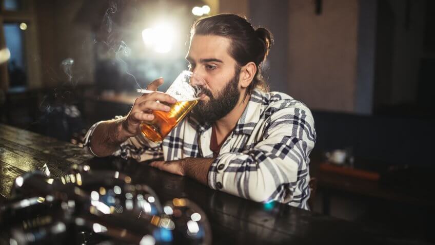 One man, sitting at the bar counter alone, he has drinking problems.