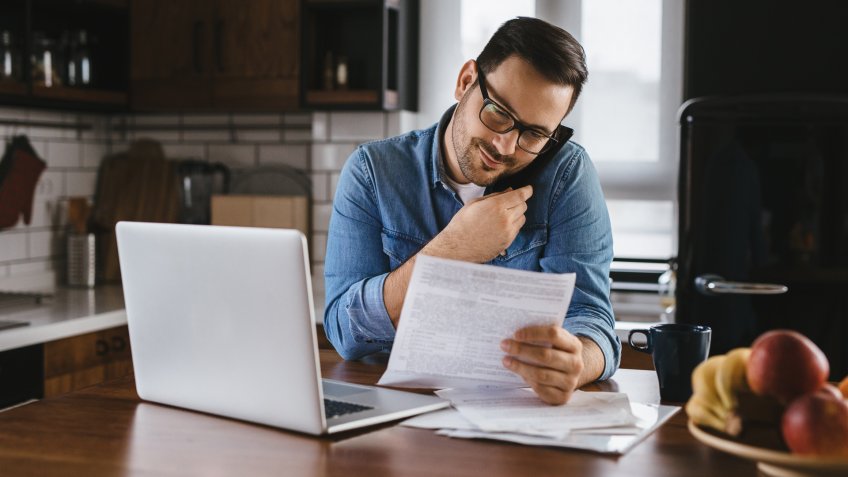 Man working with laptop computer and smart phone at home.
