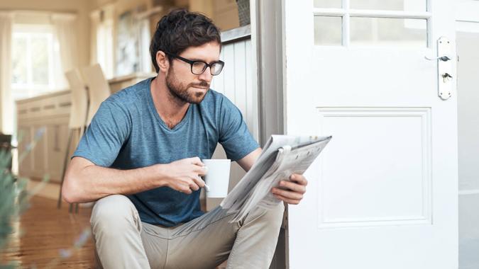 Cropped shot of a handsome young man enjoying his coffee while reading the morning paper.