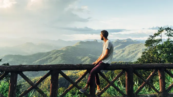 Man on the background of beautiful sunset over green mountain hills in North of Thailand.