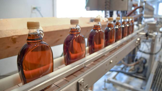 Bottles of maple syrup line a rack in a small syrup production facility on a farm in New Hampshire, USA.