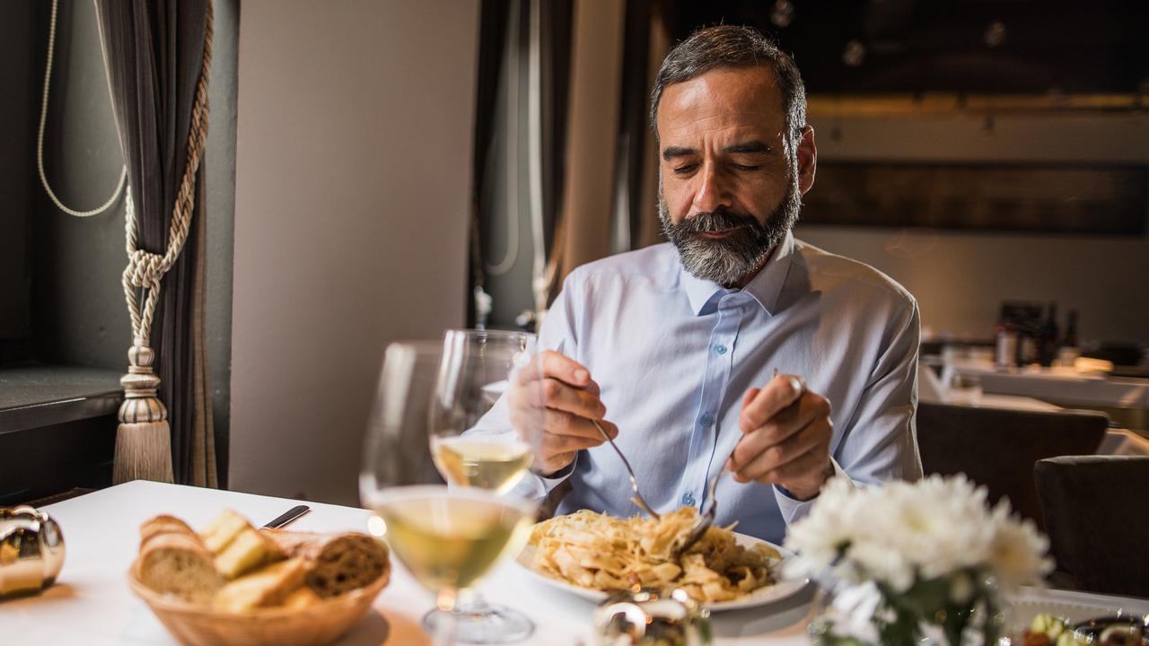 Mature man sitting in a restaurant and eating pasta for lunch.
