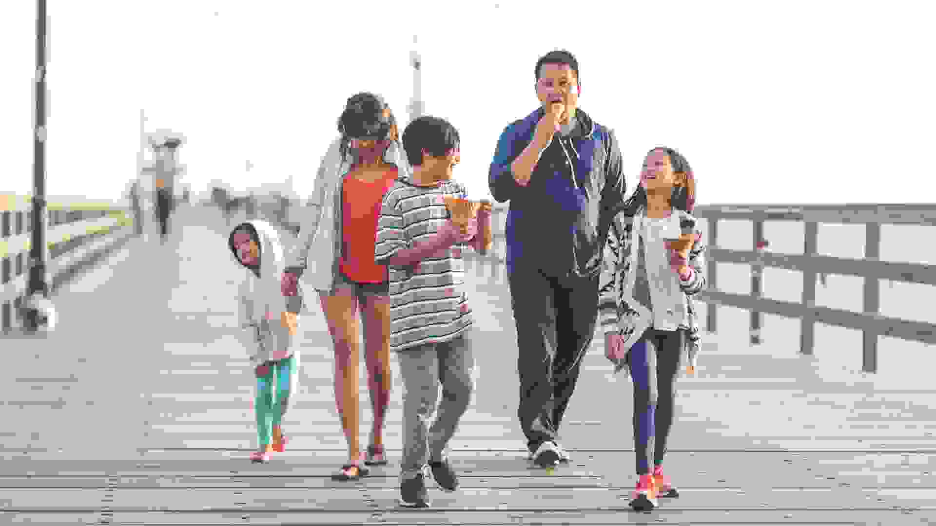 Two Filipino parents and their three children enjoy huge waffle ice cream cones on a California boardwalk by the beach.