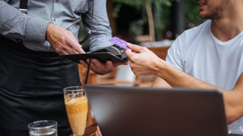 Young casually clothed businessman paying for his coffee via contactless payment.