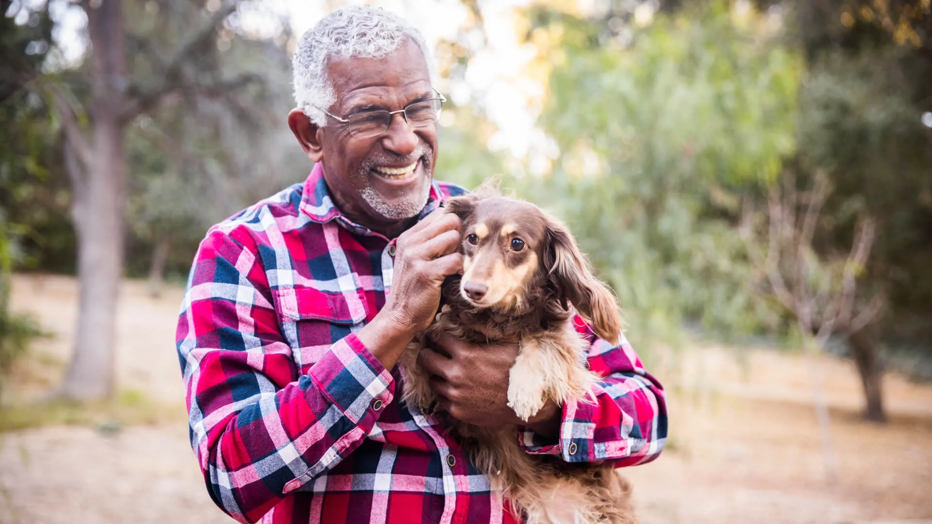 An African American senior man playing with his dog.
