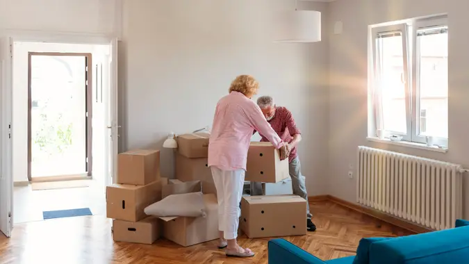 Senior Couple Carrying Boxes Into New Home on Moving Day.