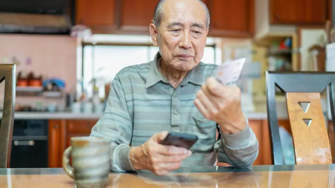 A senior man is shopping online on a smart phone.