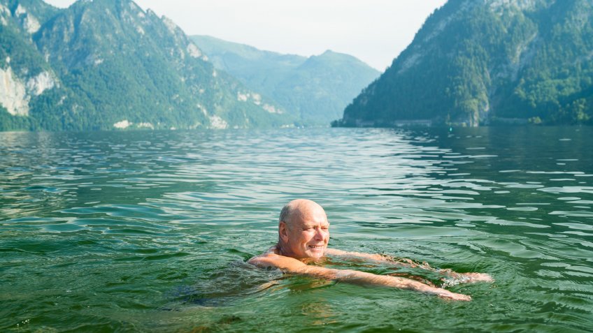 happy smiling active senior man enjoying refreshing swim in mountain lake in austria.