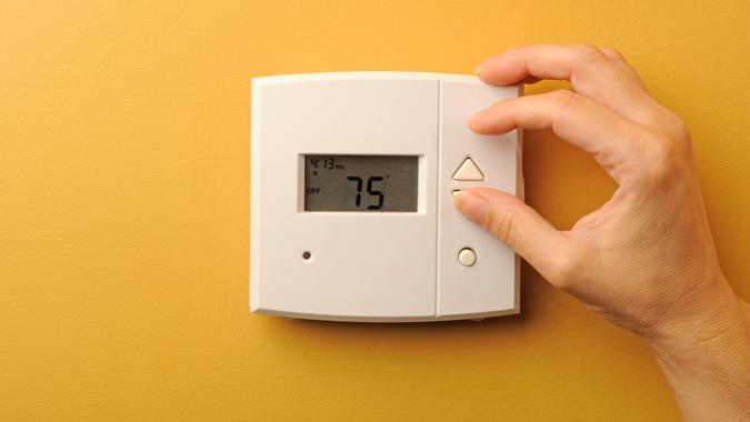 A woman turns down the thermostat.