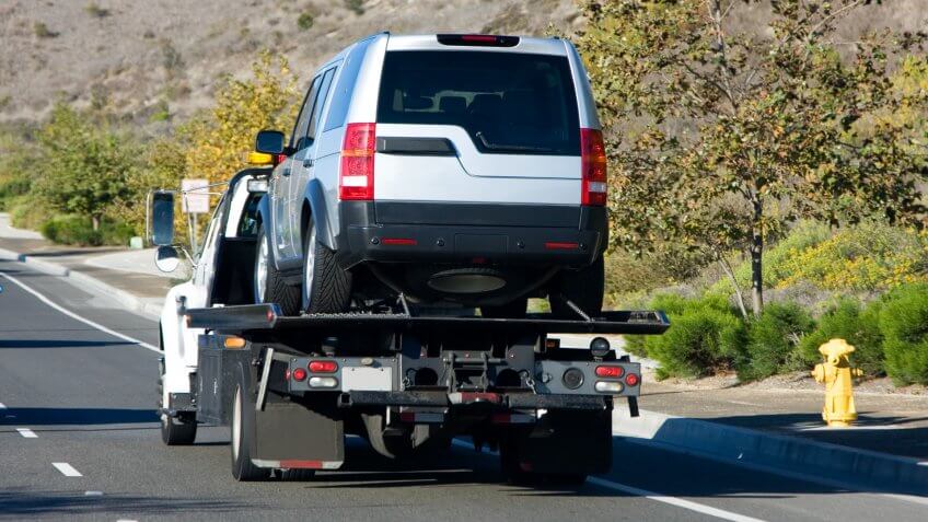 A tow truck towing a silver suv.