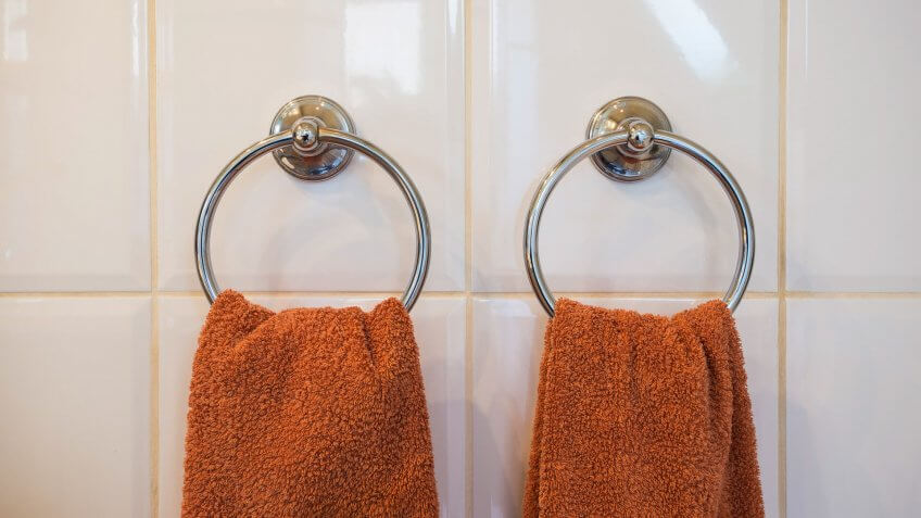 White hand towel hanging on hanger in toilet bathroom for cleaning and drying hand.