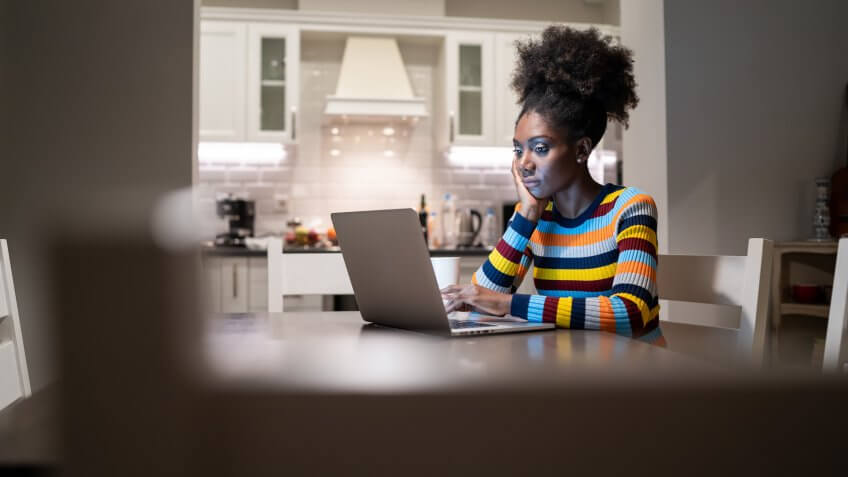African Woman using laptop at home at night.