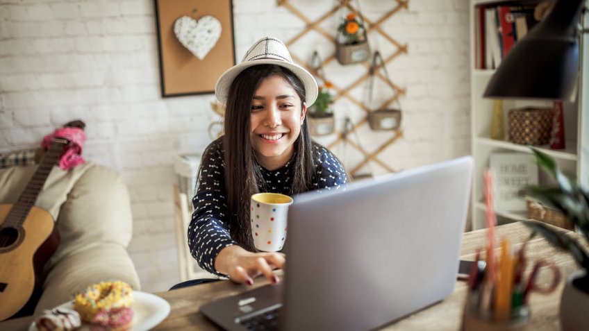 Young Asian girl working at a home with a laptop.