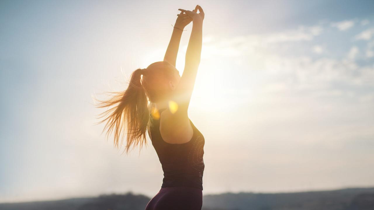 Young women in sports clothing feeling freedom in nature, doing gymnastics on sunset  with lens flare.