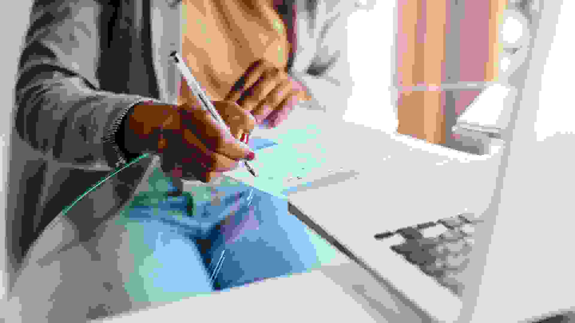 Cropped shot of a woman filling out paperwork at home.