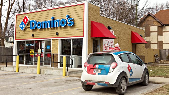 INDIANAPOLIS, IN - FEBRUARY 2019: The front of a Dominos pizza store with a small delivery car in front of the store.