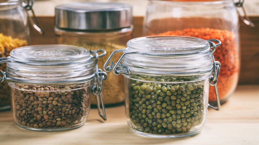 Glass jars with legumes on a table.