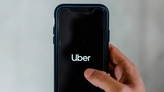 Hand holding out smartphone with Uber app on screen