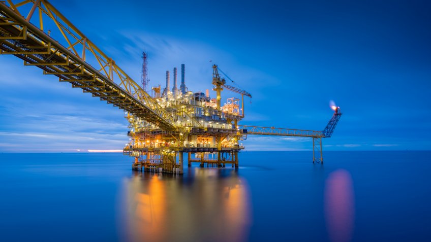 Offshore oil and gas central processing platform in sun set which produce raw gas, crude and hydrocarbon then sent to onshore refine, petrochemical industry.