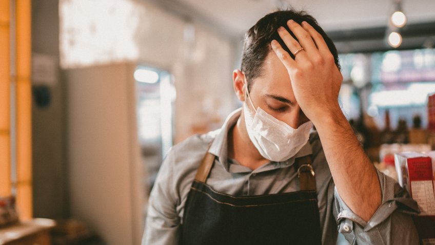 Worried owner with face mask at his small business.