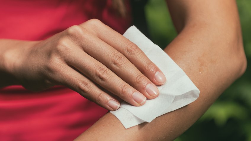 Mosquito repellent woman applying deet wet wipe on arm banner panorama background.