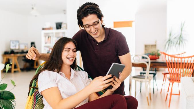 Millennial couple checking home finances at banking app from digital tablet.