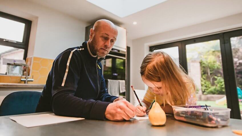 Father and his little daughter drawing together in the kitchen.
