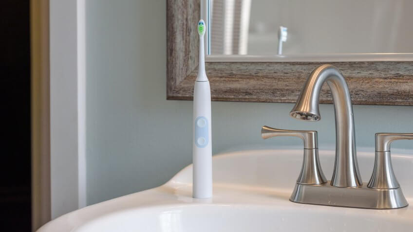 Electric toothbrush on bathroom sink - oral hygiene, personal care.
