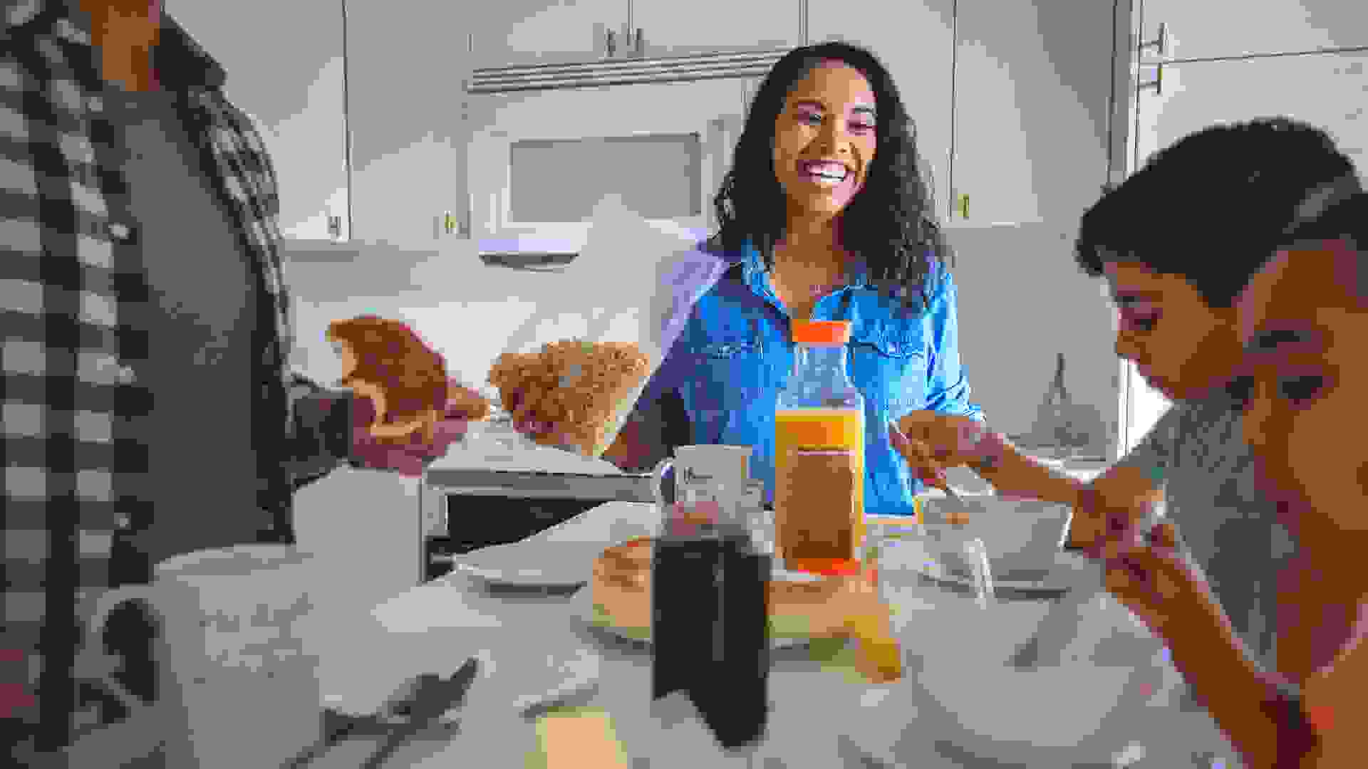 Smiling mid adult woman having breakfast with family.