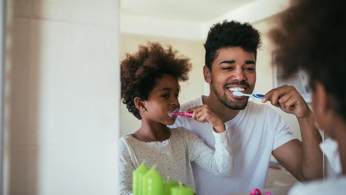 Morning activities at home African american family washing teeth in the bathroom.