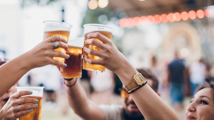Group of four friends toasting with beer on a music festival.