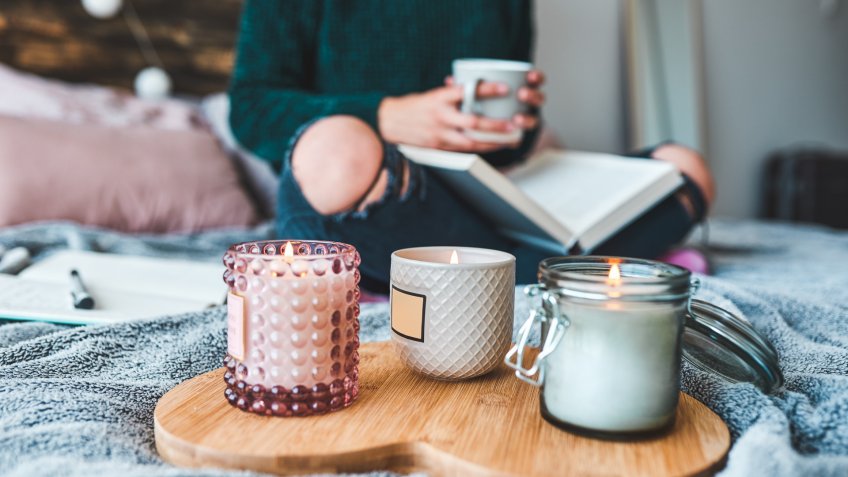 Cropped shot of an unrecognizable young woman relaxing with a book and a cup of coffee on her bed at home.