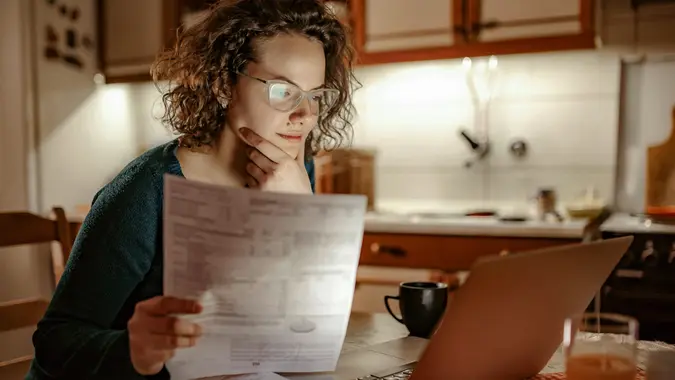 Woman examining her bills, trying to resolve situation.