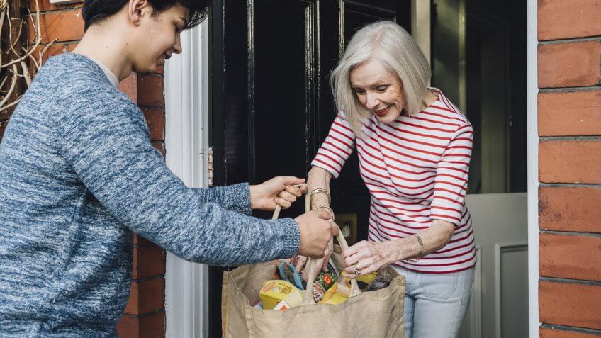 Teenage boy is delivering some groceries to an elderly woman.