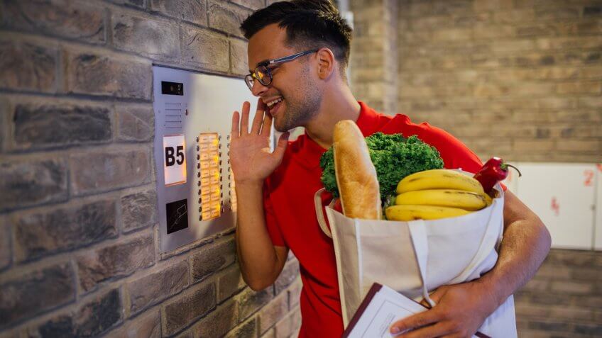 Delivery man informing his customer via intercom that the order has arrived.