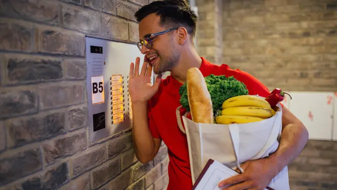 Delivery man informing his customer via intercom that the order has arrived.
